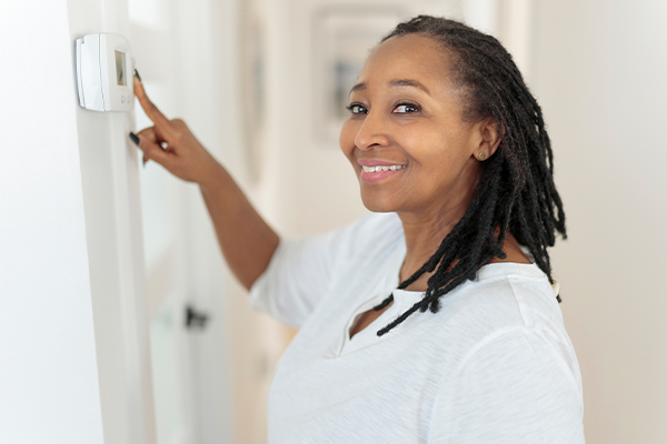 Woman smiling and pointing at her thermostat